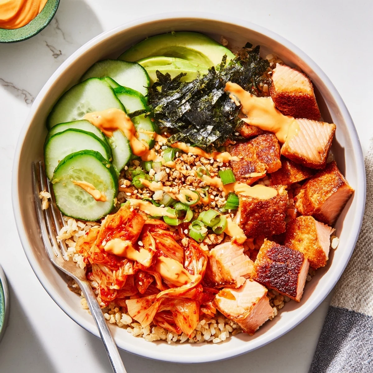 Crispy Salmon Rice Bowl topped with kimchi, avocado, and drizzled spicy mayo.
