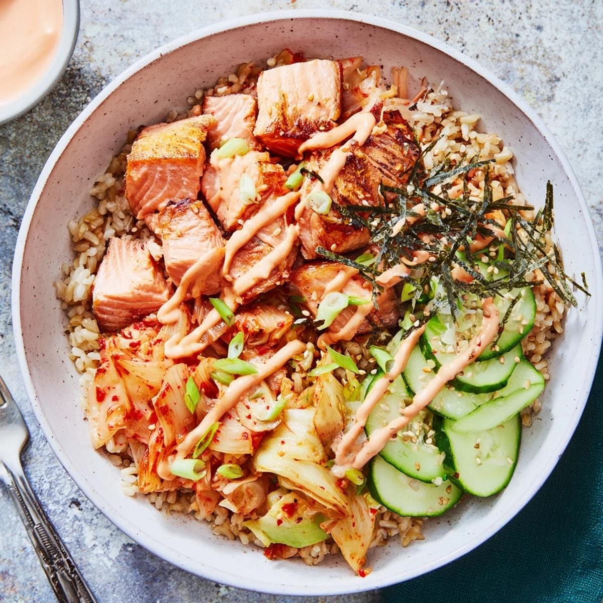 Delicious crispy salmon rice bowl featuring savory garlic and fresh cucumbers.
