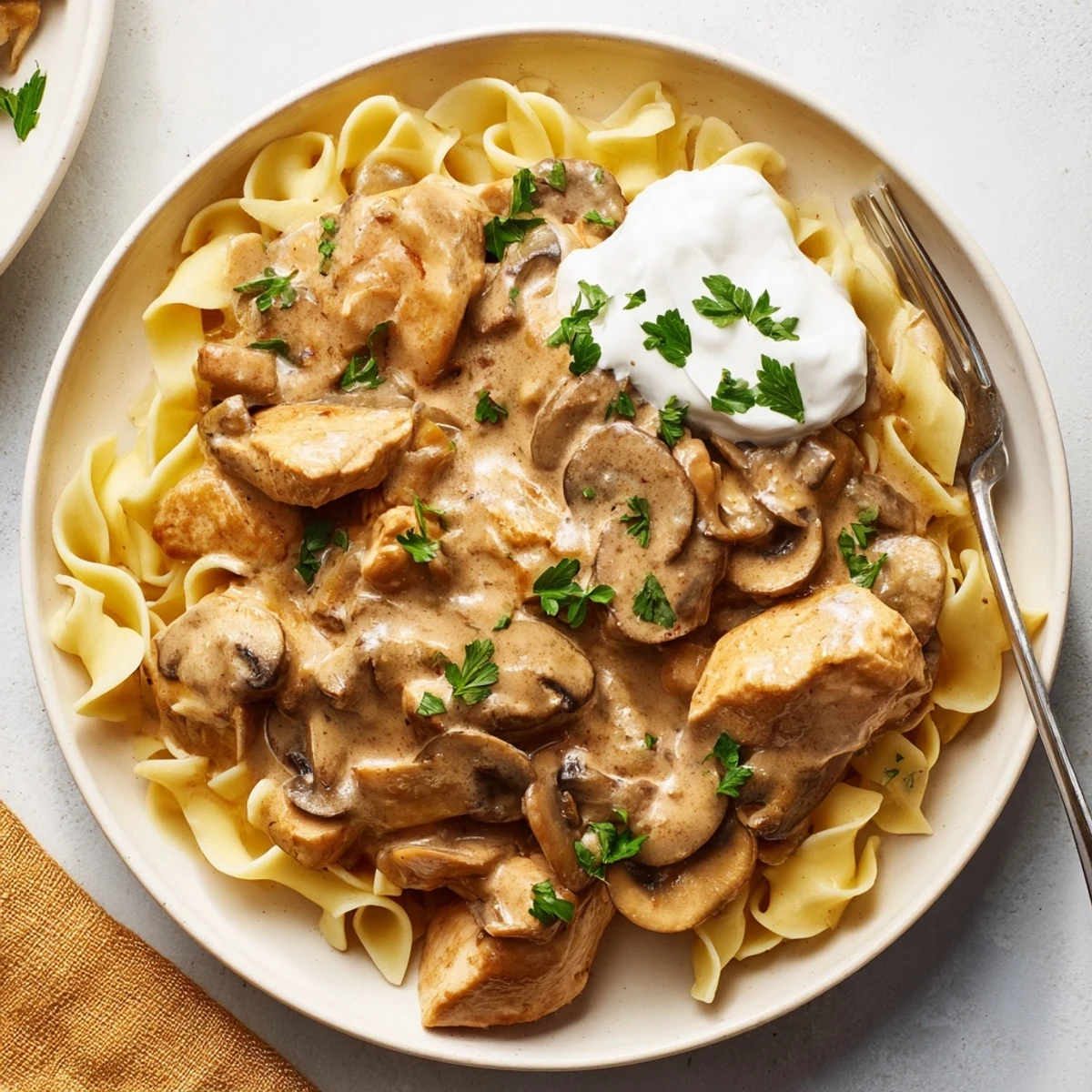 Creamy Chicken Stroganoff served over tender egg noodles with fresh parsley garnish.