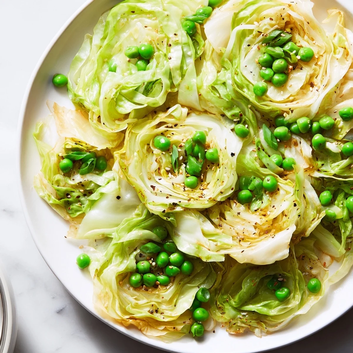 Steaming cabbage stir-fry with bright green peas and savory soy sauce glaze, a quick vegetarian meal.