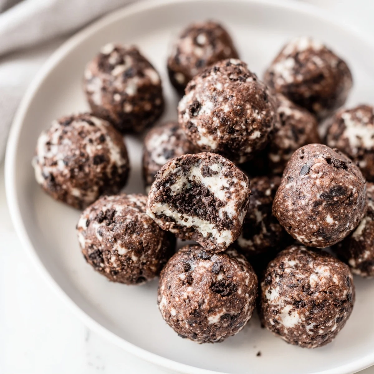 Velvety Cream Cheese Oreo Protein Balls piled on a tray, a no-bake, protein-packed dessert or snack option.