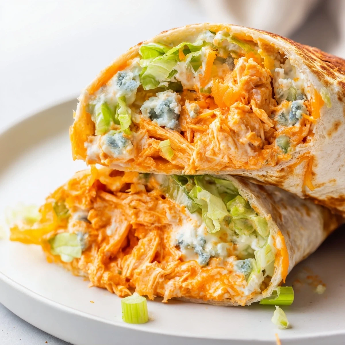 A close-up of a delicious Buffalo Chicken Dip Wrap, showing the creamy chicken and fresh lettuce inside.
