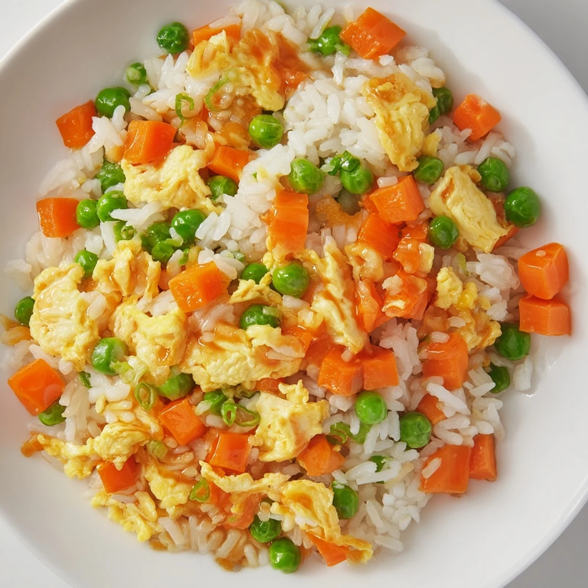 A close-up of steaming Egg Fried Rice, showcasing vibrant veggies and seasoned, leftover rice.