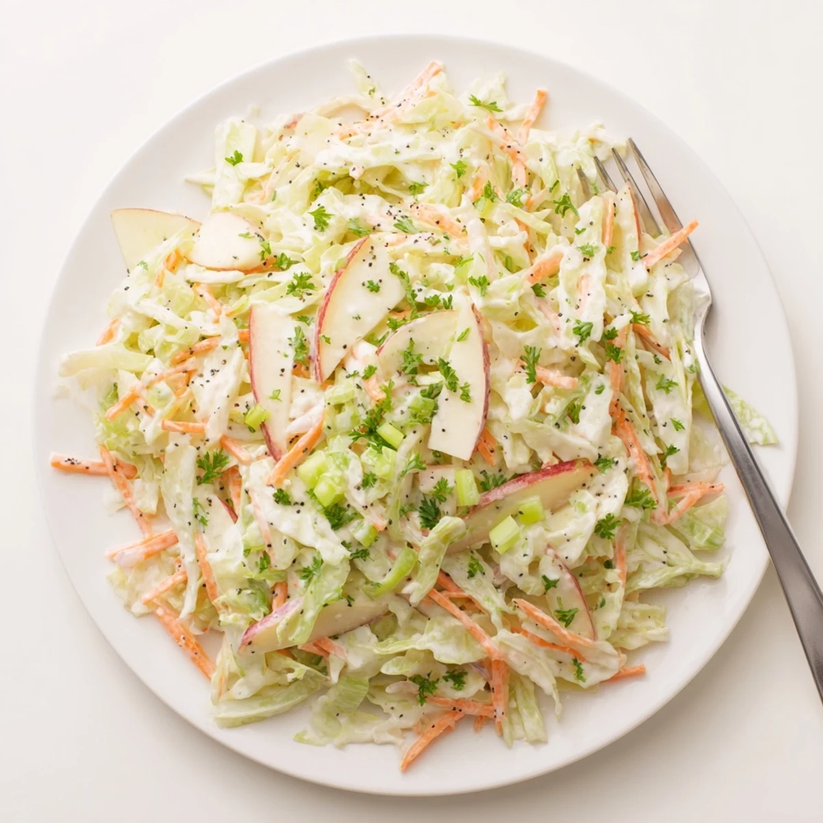A colorful bowl of Green Cabbage and Apple Slaw, garnished with fresh parsley and poppy seeds, ready for a picnic.  