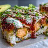 Golden melted cheese tops this Spicy Salmon Sushi Bake, garnished with fresh avocado and a drizzle of spicy mayo.