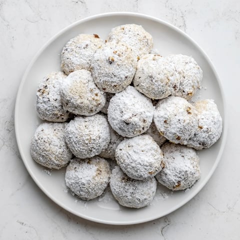 Warm, golden Budget-Friendly Snowball Cookies coated in a generous dusting of sweet powdered sugar.