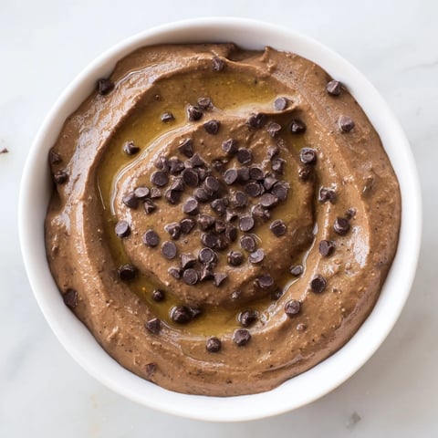 Rich, creamy chocolate hummus ready to be scooped up with fresh strawberries for a sweet treat.
