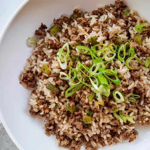 Steaming Cajun Dirty Rice, a flavorful Southern main dish, ready to serve with fresh green onions.