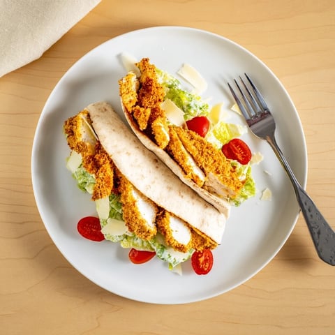 Golden-brown herbed chicken cutlets nestled in a warm pita pocket, stuffed with crisp Caesar salad and shaved Parmesan.  