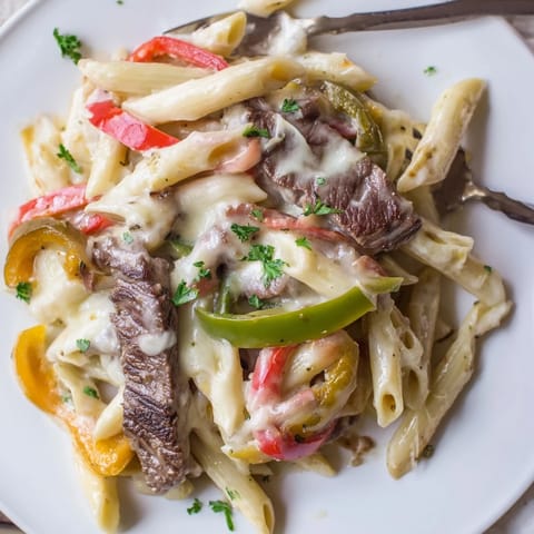 Creamy and savory Philly Cheese Steak Pasta topped with fresh parsley and melted cheese.  