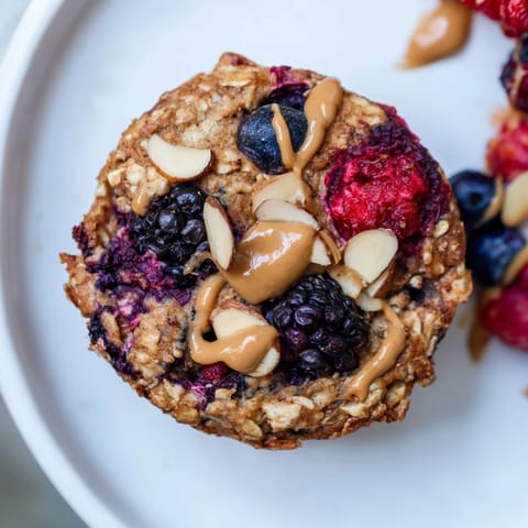 Freshly baked oatmeal cups, showcasing mixed berries and creamy almond butter, perfect breakfast.
