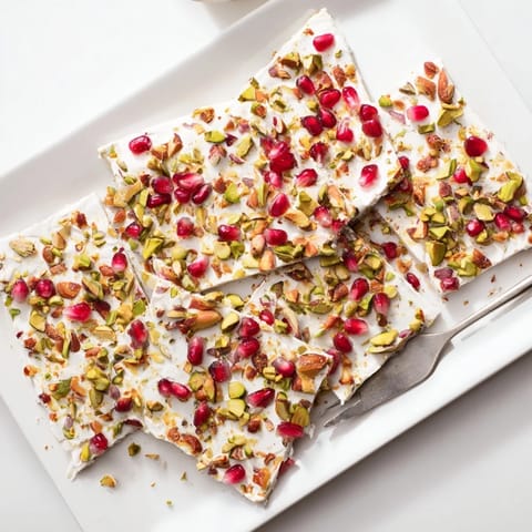 Close-up of Frozen Yogurt Bark: frozen treat with bright red pomegranate and green pistachios sprinkled.