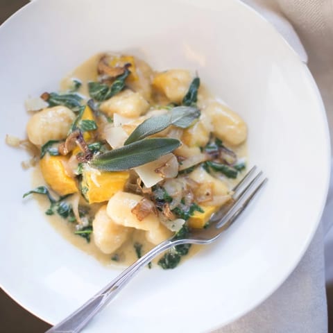 Close-up of golden One-Pot Pumpkin Sage Gnocchi, with crispy sage leaves over the creamy sauce.