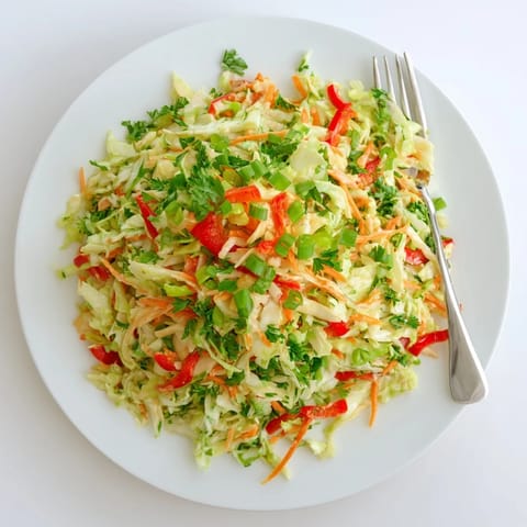 Healthy vegan Sauerkraut Slaw served chilled, topped with crisp red bell pepper slices, green onions, and fresh parsley garnish.  