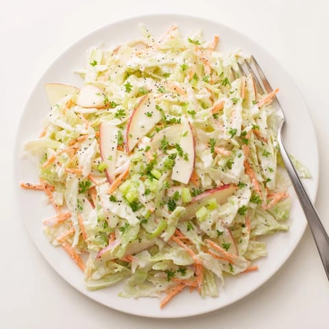 A colorful bowl of Green Cabbage and Apple Slaw, garnished with fresh parsley and poppy seeds, ready for a picnic.  