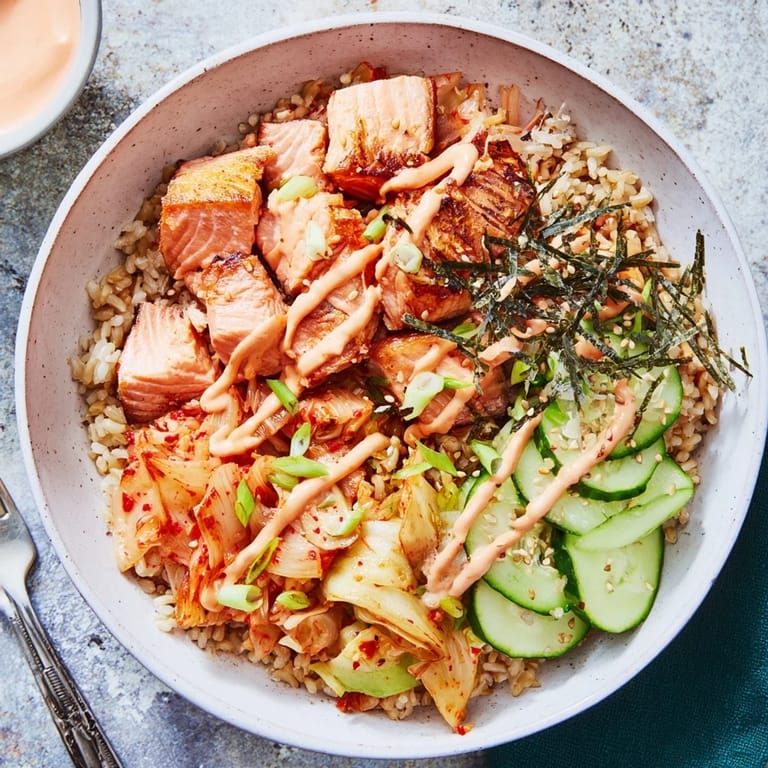 Delicious crispy salmon rice bowl featuring savory garlic and fresh cucumbers.